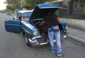Man repairs a 1957 Chevrolet car on a street in Havana